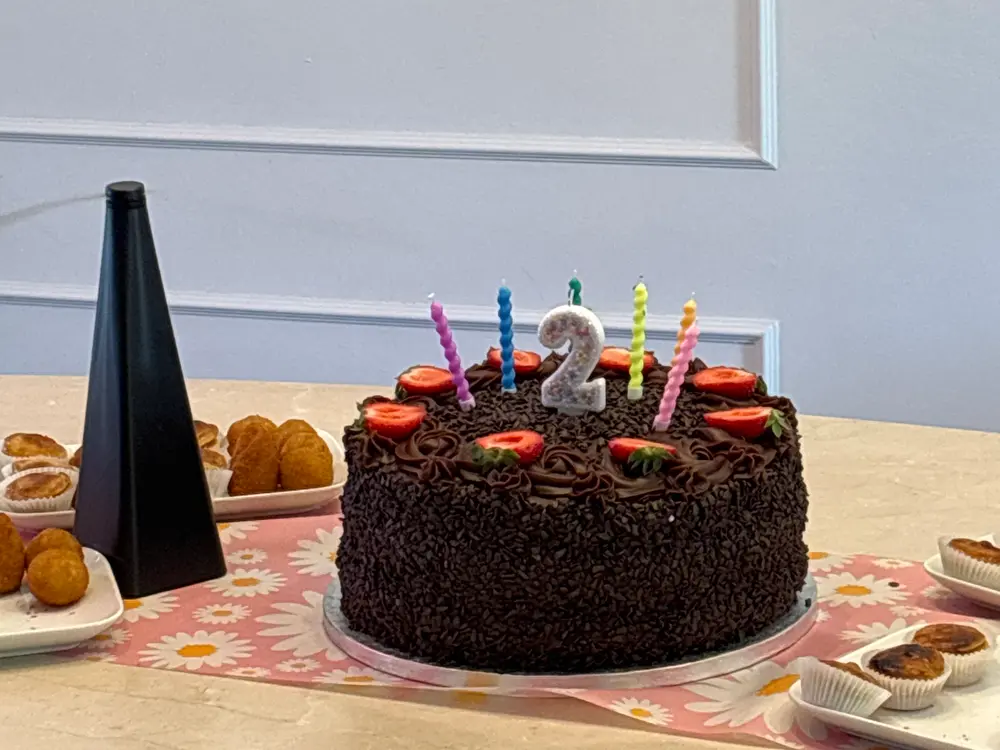 Aniversário: bolo de chocolate com velas coloridas e o número 2, cercado de docinhos
